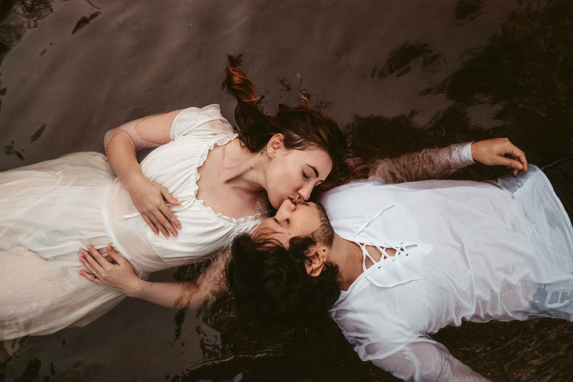 A couple lying together and kissing in dark water in Galax, Virginia