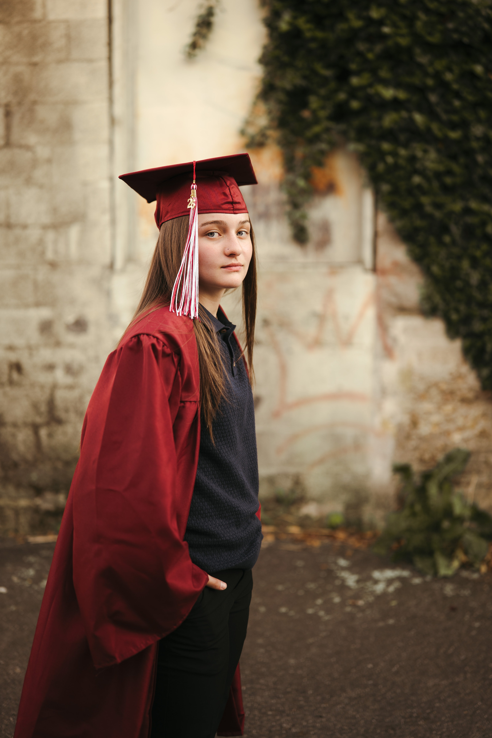 A graduate in a maroon cap and gown beside an ivy-covered stone wall, Galax VA high school graduate photo