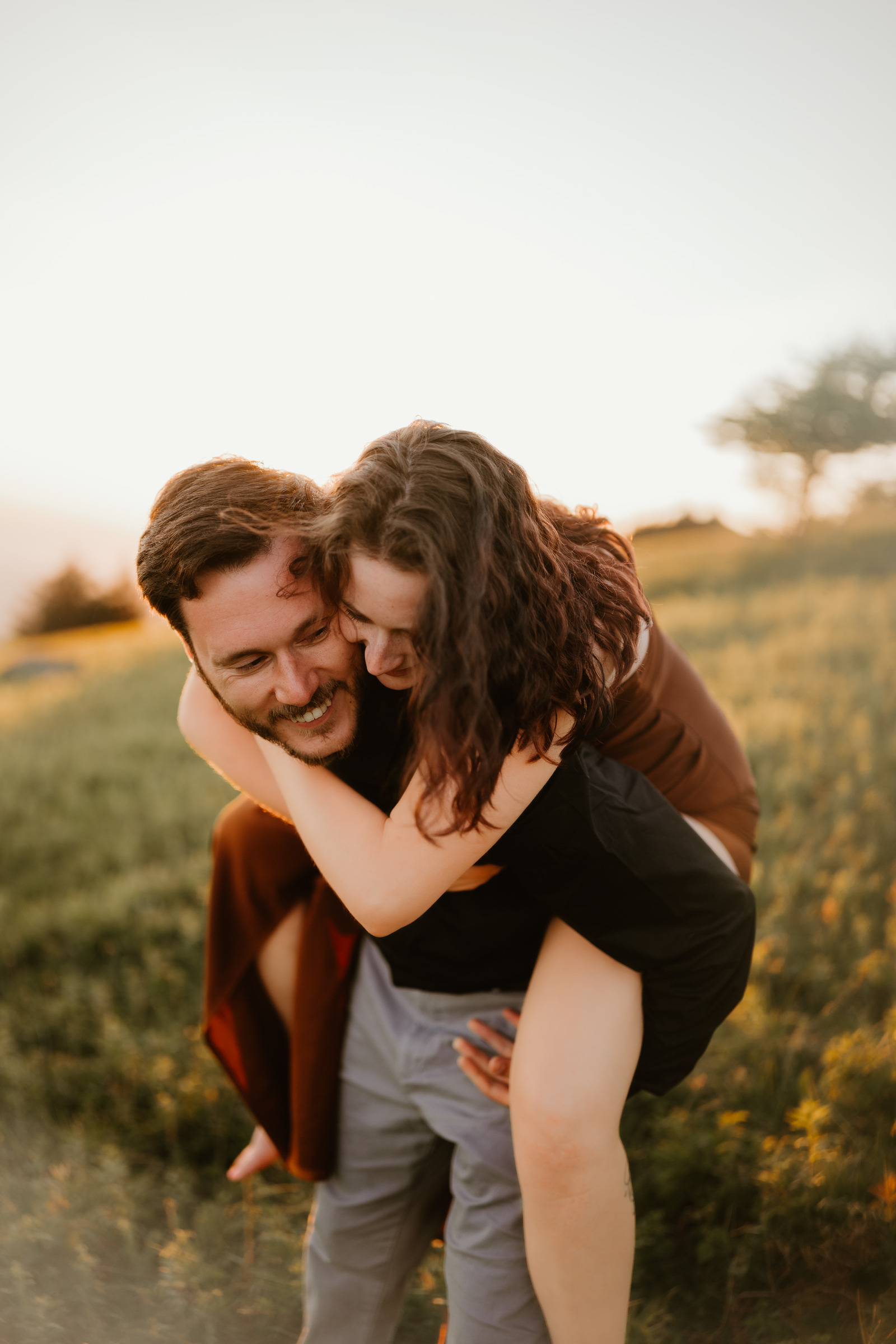A laughing couple sharing a piggyback ride at golden hour, Grayson Highlands State Park River Songs Photos