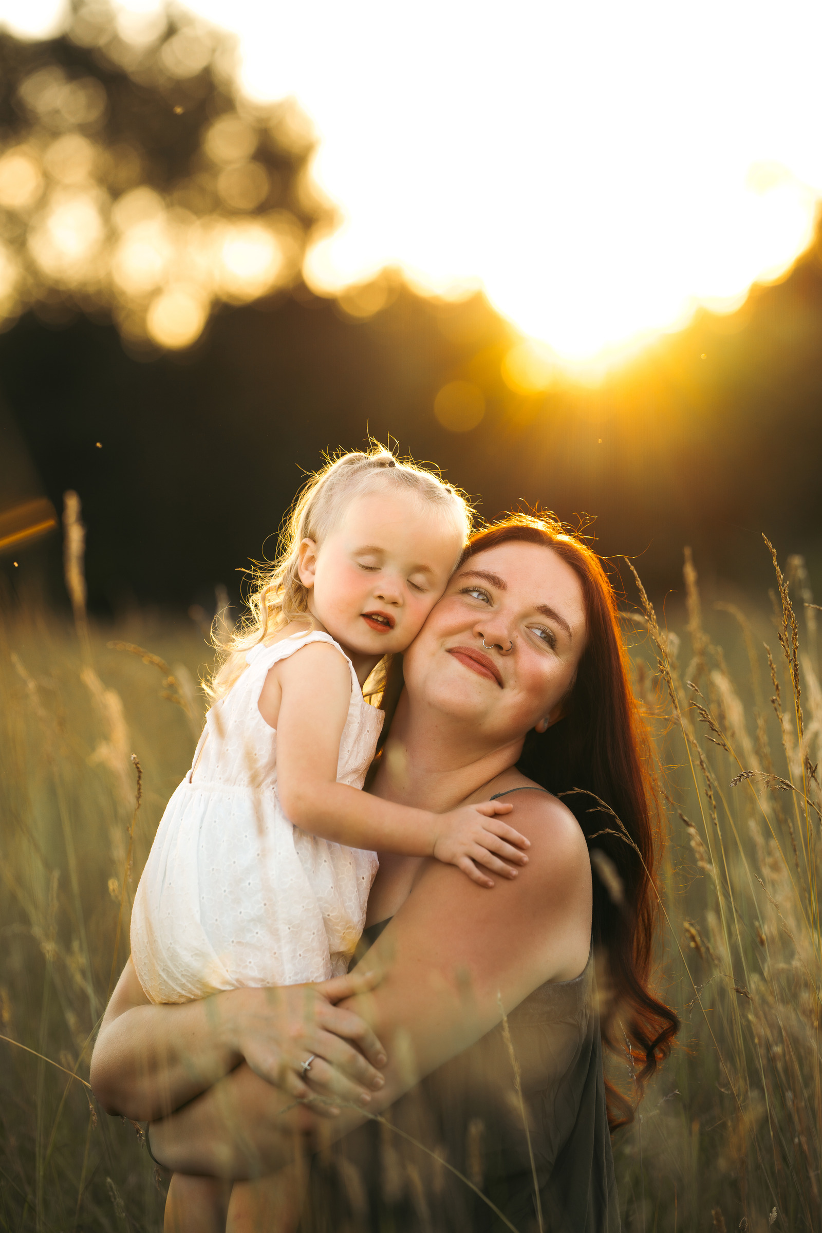 A mother holding her young blonde daughter in warm evening light, Pearisburg VA River Songs Photos